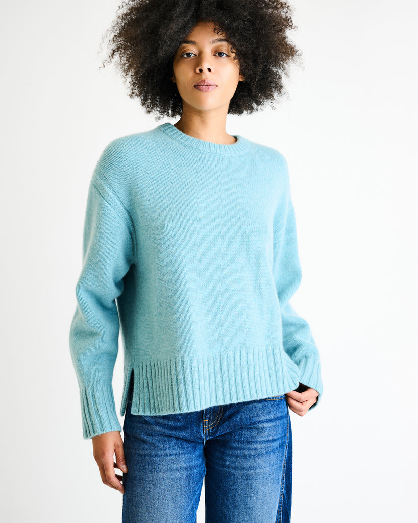 Person wearing a light blue sweater and blue jeans on a white background